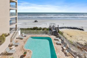 a swimming pool next to a beach and the ocean at Palm House 3B with oceanfront views, pool, and private beach access in New Smyrna Beach