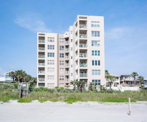 a large white apartment building on the beach at Palm House 3B with oceanfront views, pool, and private beach access in New Smyrna Beach