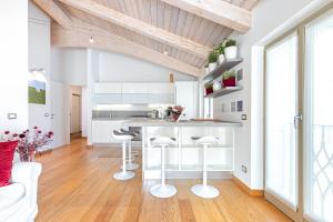 a kitchen with white cabinets and a counter with stools at La Tessella - Suite Centrale con Posto Auto Gratis in Alba