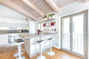 a kitchen with white cabinets and bar stools at La Tessella - Suite Centrale con Posto Auto Gratis in Alba +30 photos