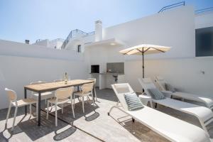 Un patio con una mesa y sillas y una sombrilla. en Modern Villa with Private Pool Near Baleal Beach, en Atouguia da Baleia