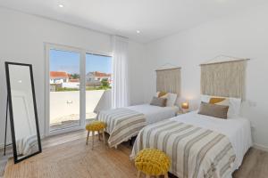 Dos camas en una habitación blanca con ventana. en Modern Villa with Private Pool Near Baleal Beach, en Atouguia da Baleia