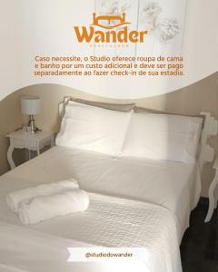 a poster of a bed with white sheets and pillows at Studio do Wander in Amparo