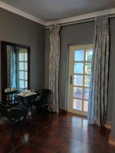 a dining room with a table and chairs and a window at Kimberland Guest House Block 10 in Gaborone