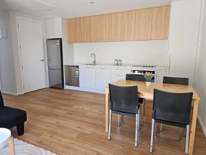 a kitchen with a wooden table and black chairs at Amazing remarkable view, 7 min from airport in Queenstown
