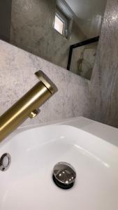 Un baño con lavabo con grifo y espejo. en Hotel de Touraine Belleville, en París