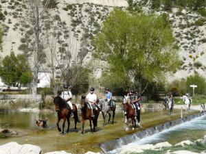 un grupo de personas a caballo cruzando un río en Apartamentos Tío José María, en Hinojares