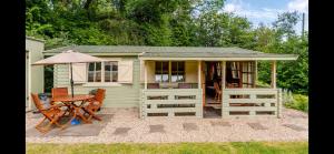 a small green cottage with a table and chairs at Family friendly sunny Log Cabin in Wimborne Minster