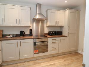Una cocina con gabinetes blancos y una estufa. en 5 Ashcroft Mews, en Seaham