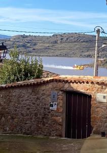 a stone building with a door and a body of water at La Casa Rural de Pálmaces in Pálmaces de Jadraque