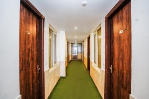 a corridor with wooden doors and a green floor at HOTEL Le GRAND in Jāmb