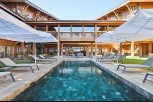 a pool with chairs and umbrellas next to a building at Apartment 78 by the pool in Bansko