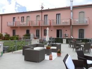 a patio with tables and chairs in front of a pink building at Hotel Lucerna in Castiglione della Pescaia