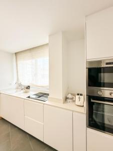 a white kitchen with a sink and a microwave at Apartamento Nosa Terra by ALÔGA in Cee