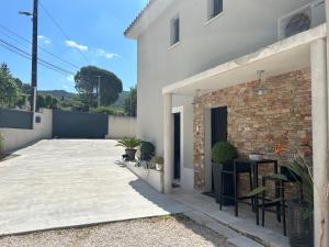a white house with a brick wall and a patio at La Chambre de Mijeane in Gémenos