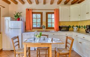 a kitchen with white cabinets and a table and chairs at La Charmille in Saint-Étienne-lʼAllier