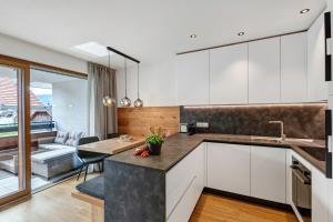 a kitchen with white cabinets and a dining room with a table at Appartement Sonnlicht Pfalzen in Falzes