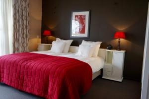 een slaapkamer met een groot bed en een rode deken bij Hotel Martensplek in Tiendeveen