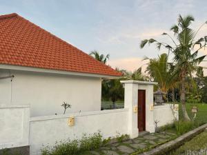 a white house with a fence and palm trees at Villa in Ubud