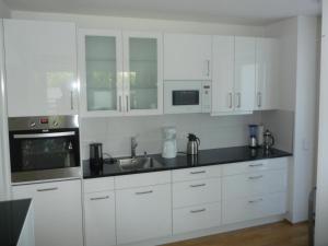 a kitchen with white cabinets and a sink and microwave at 4 Ferienwohnung Franziska in Oberstaufen