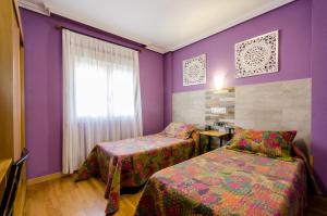 two beds in a room with purple walls at Las Abadías in Mérida