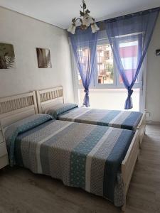 two beds in a bedroom with two windows at APARTAMENTO DANAE centro ESS00359 in Zumaia