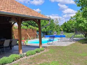 a pavilion with a table and chairs next to a pool at Melody Huis in Poroszló