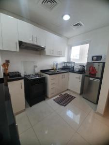 a kitchen with white cabinets and a black stove at Damac Hills 2- 3BR Townhouse - Homeyvillas in Dubai