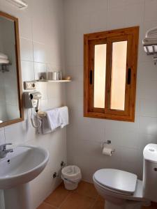 a bathroom with a sink and a toilet and a mirror at Hostal Las Dunas in El Cabo de Gata