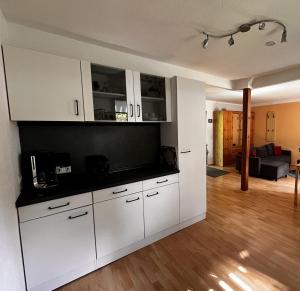 a kitchen with white cabinets and a living room at Ferienwohnung Magdalena in Hohnstein