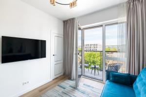 a living room with a blue couch and a large window at City Center Apartamentai Šatrijos g in Vilnius