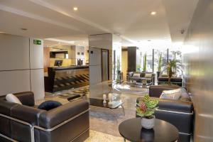 a living room with leather couches and a table at Slaviero Hotel Curitiba Batel in Curitiba +69 photos