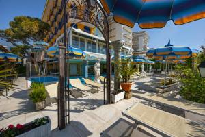 a hotel with blue umbrellas and chairs and a pool at Hotel Napoleon in Lido di Jesolo