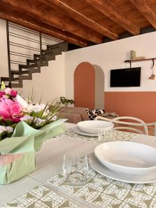 明乔河畔的瓦雷奇奥La casa di Nina - Appartamenti Deluxe的用餐室,配有带盘子和鲜花的桌子