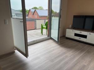 a living room with a television and a balcony at 3 Zimmer Ferienwohnung Nummer 1 in Hilter am Teutoburger Wald