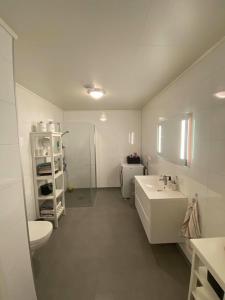 a white bathroom with a sink and a toilet at Hagebyveien appartment - City Centre in Leknes