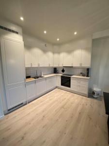 a kitchen with white cabinets and a wooden floor at Hagebyveien appartment - City Centre in Leknes