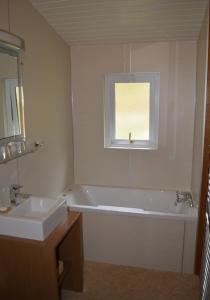 a bathroom with a tub and a sink and a window at Crowlin Lodge in Duirinish