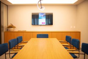 einen Konferenzraum mit einem Tisch und einem TV an der Wand in der Unterkunft Studio 25 andar a 350m da Beira Mar com Rooftop in Fortaleza + 26 Fotos