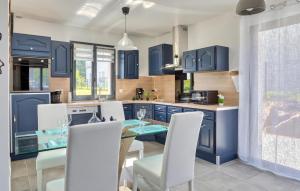 a blue kitchen with a glass table and white chairs at Maison Proche Mer in Saint-Valéry-en-Caux