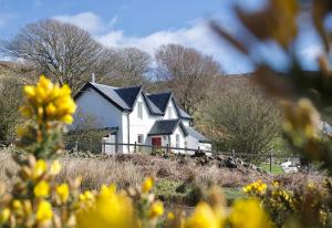 a white house with black roof on top of a hill at Grouse Cottage in Kilninian
