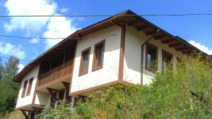 a white house with a wooden roof at Chepelare Holiday Guest House in Chepelare