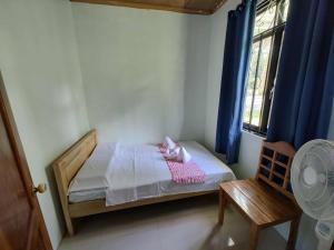 een kleine slaapkamer met een bed en een raam bij The Red Roof in Batuan