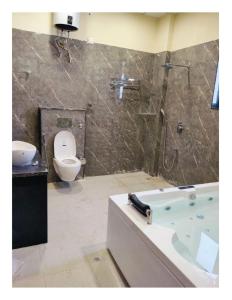 a bathroom with a bath tub and a toilet at Pink Mahal Hotel & Resort in Jaipur