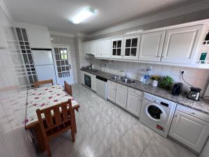 a kitchen with a table and a washing machine at Suíte-Refúgio á Beira-Mar Apartamento Partilhado in Viana do Castelo
