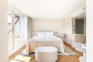 a white bedroom with a bed and a stool at Hotel Bommeljé in Domburg +108 photos