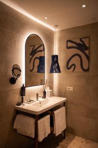 a bathroom with a sink and a mirror and towels at Cala Ponte, a Tribute Portfolio Hotel in Polignano a Mare