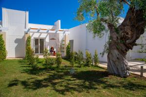 a white house with a tree in the yard at Cala Ponte, a Tribute Portfolio Hotel in Polignano a Mare