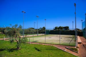a tennis court with a net in a field at Cala Ponte, a Tribute Portfolio Hotel in Polignano a Mare