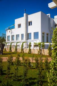 a white building with trees in front of it at Cala Ponte, a Tribute Portfolio Hotel in Polignano a Mare
